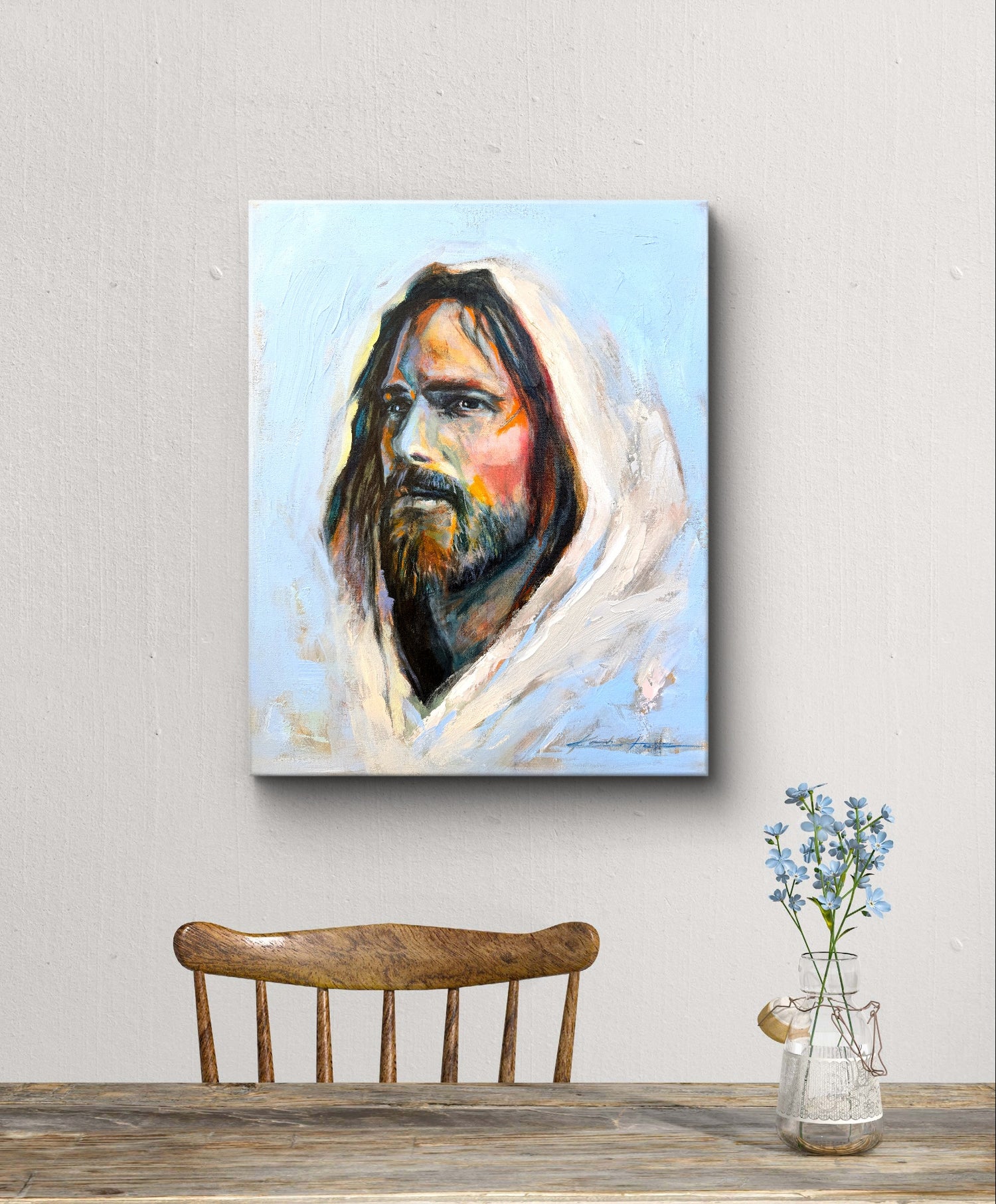 Minimalist dining table with a painting of Jesus hung on the wall, depicting jesus with vibrant color representing diversity and love. Titled :The color of Grace. 