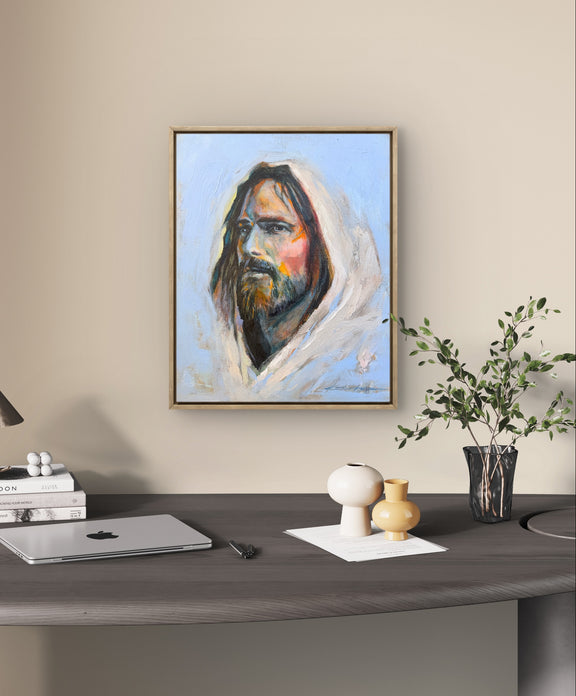 A framed portrait of Jesus on the wall over a desk in an office with a small plant. 