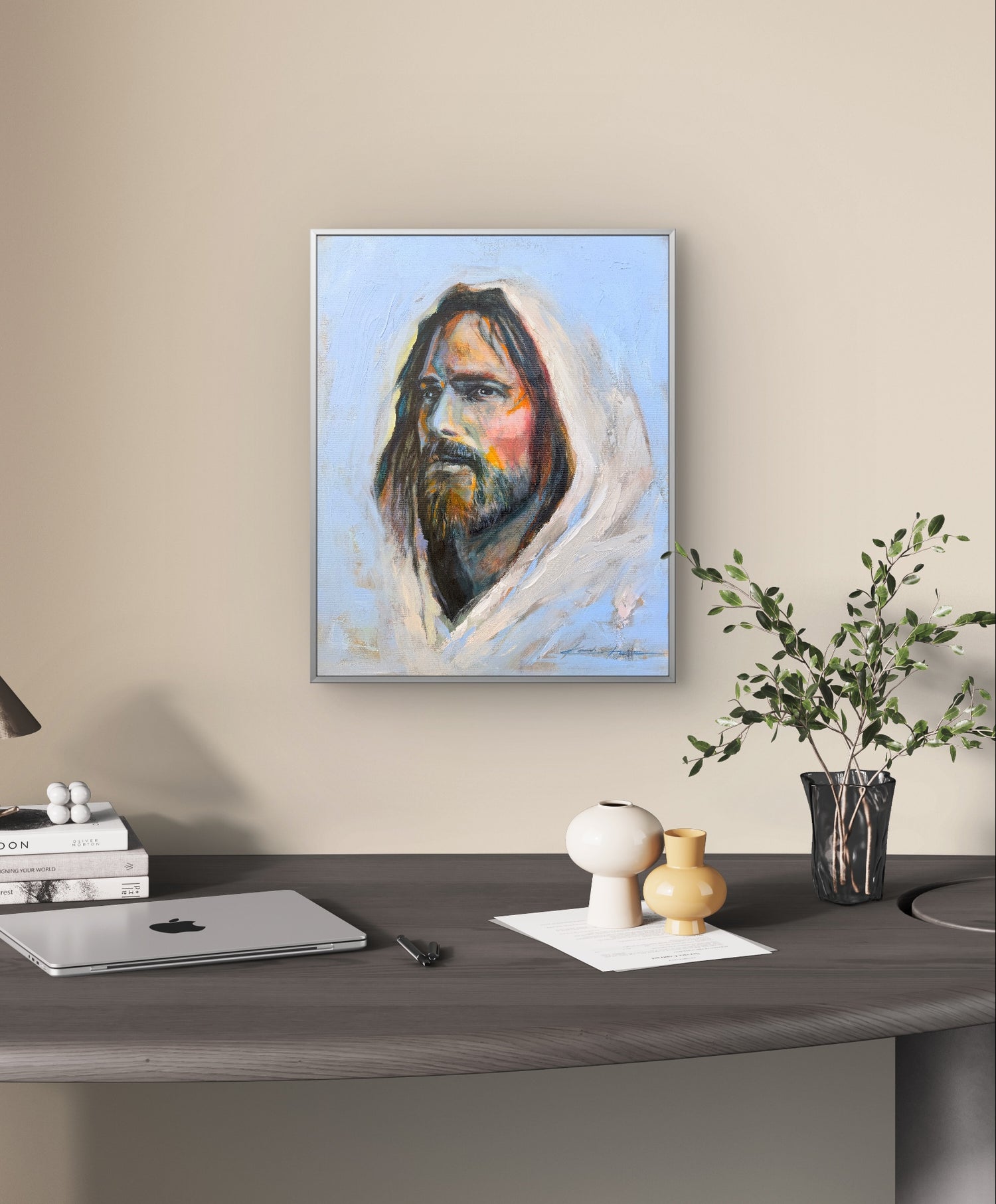 Framed Original Oil Painting, a portrait of Jesus with big brushstrokes and thick paint, a lot of texture and vibrant colors hanging over a desk in an office with a plant to the bottom right. 
